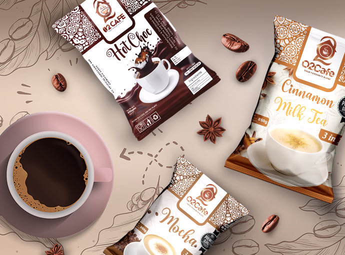 Top-down view of a coffee cup surrounded by O2 Cafe Mocha, Cinnamon Milk Tea, and Hot Choc packets along with roasted beans, showcasing our tea and coffee premixes in Sri Lanka